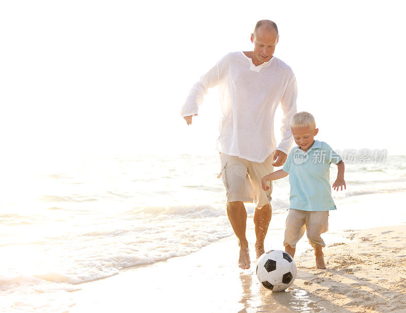 Father and Son playing Football on a Beach.重复图片